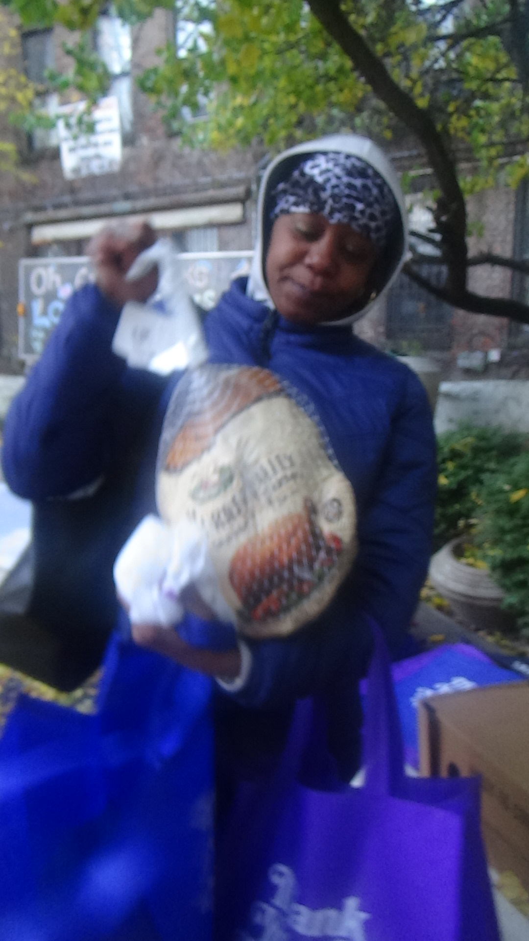 Woman carrying a turkey and shopping bag after receiving holiday support